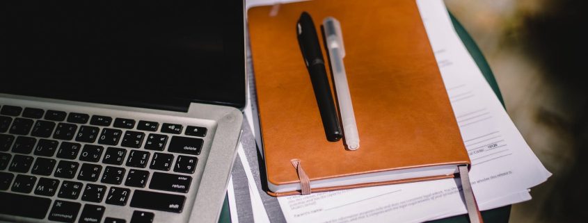 planner and pens on table with laptop